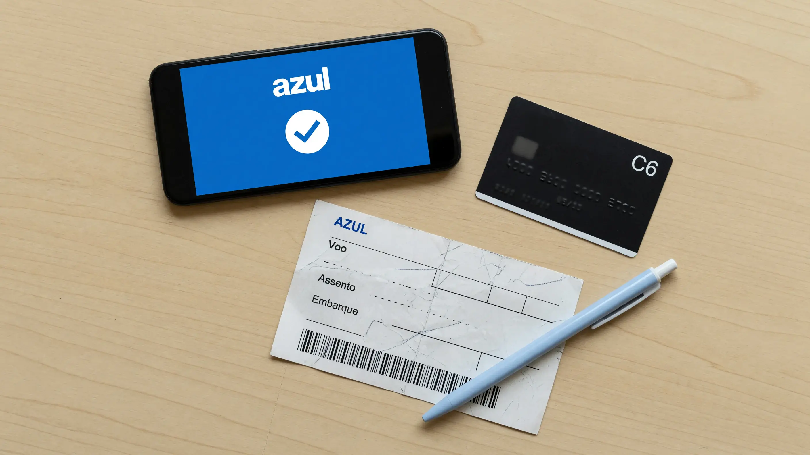 Tela de transferência de pontos aberta no celular, com a confirmação do envio dos pontos para o Azul Fidelidade, sobre uma mesa com cartão e passagem — sem número de conta ou de cartão legível.