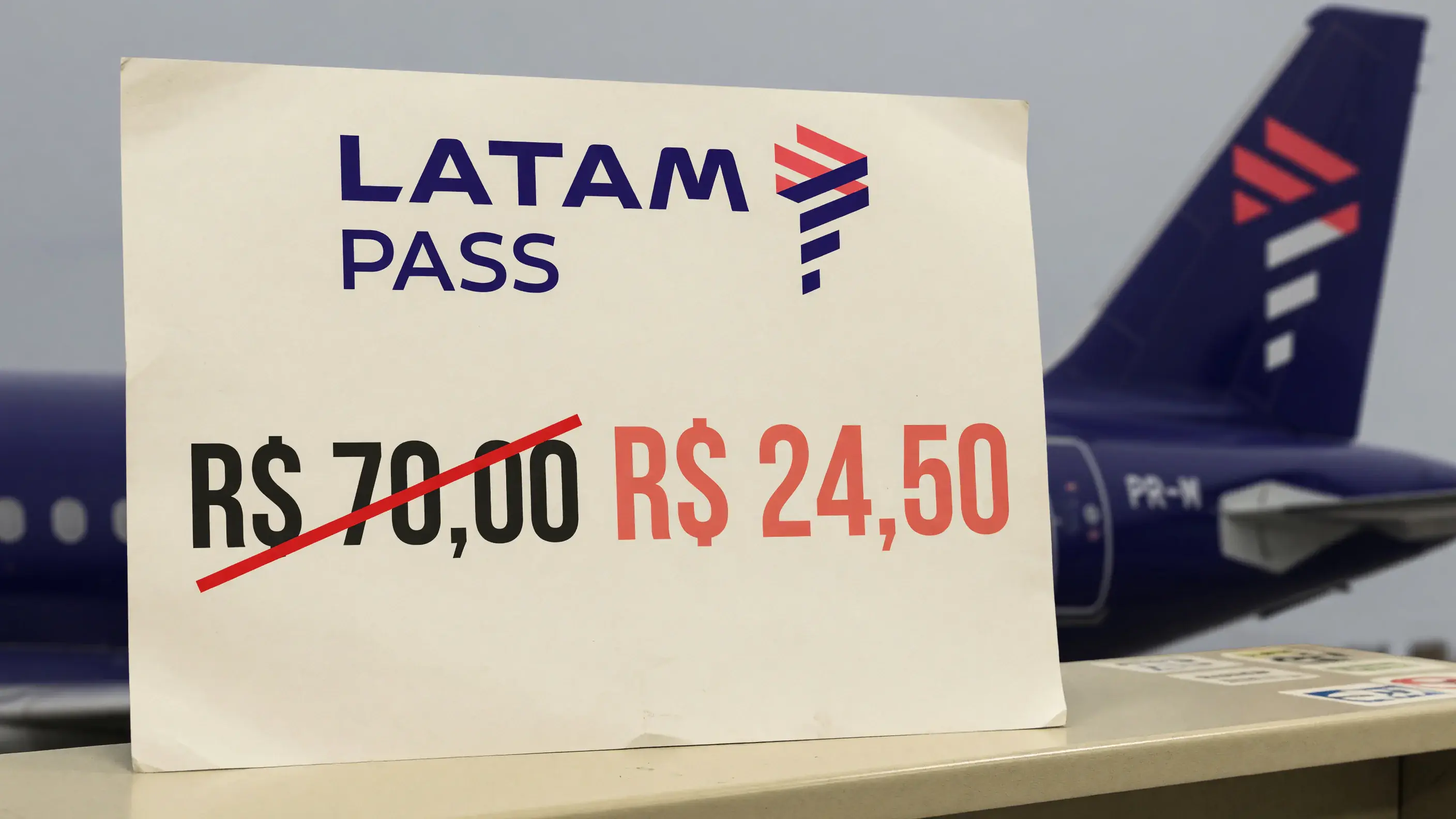 Ilustração com o logotipo do LATAM Pass em destaque e, ao fundo, a cauda de um avião na pintura da LATAM.