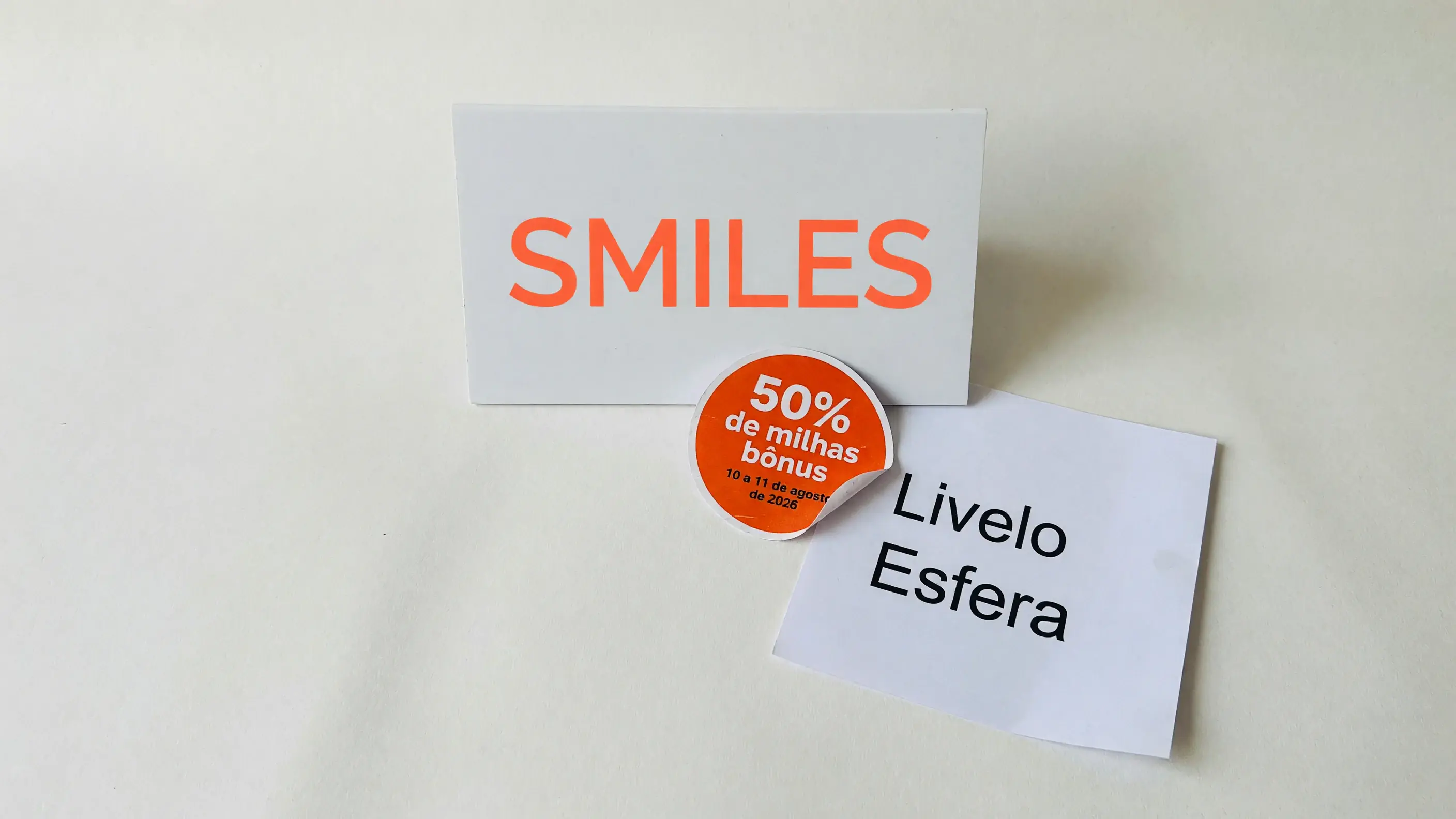 Ilustração da rodada de transferência bonificada da Smiles: a marca Smiles ao lado de um selo de 50% de milhas bônus e de uma folha com os nomes Livelo e Esfera.